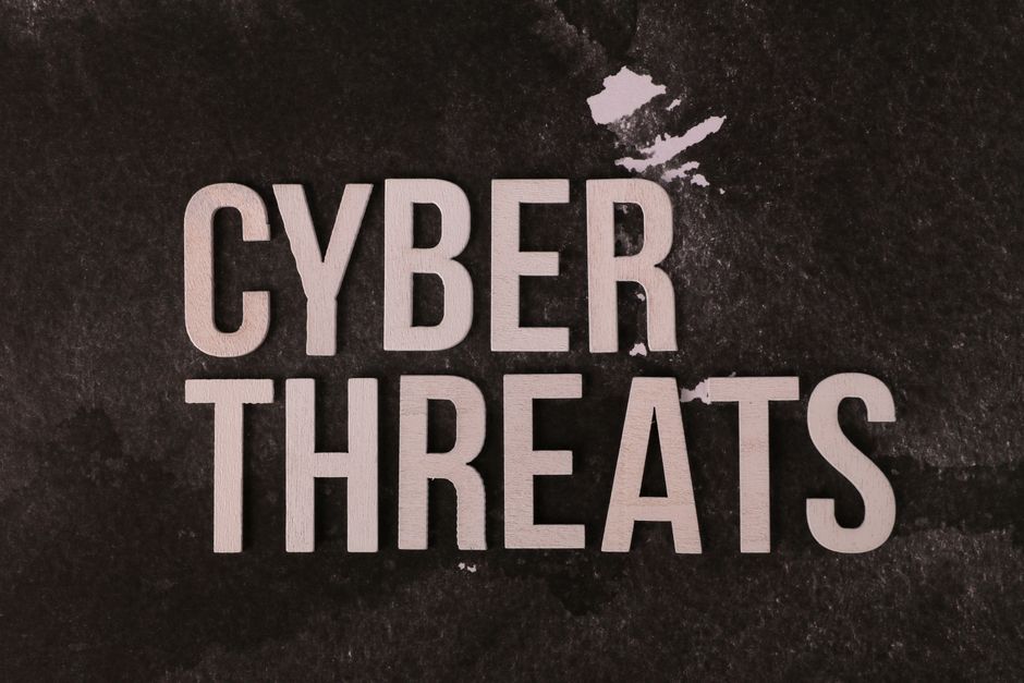 The phrase 'Cyber Threats' on a dark textured background emphasizing digital security risk