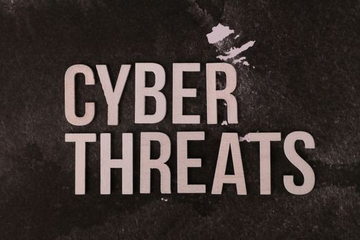The phrase 'Cyber Threats' on a dark textured background emphasizing digital security risk